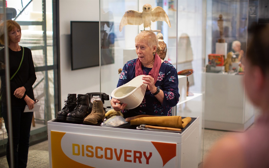 A museum volunteer holding an item during a guided tour. 