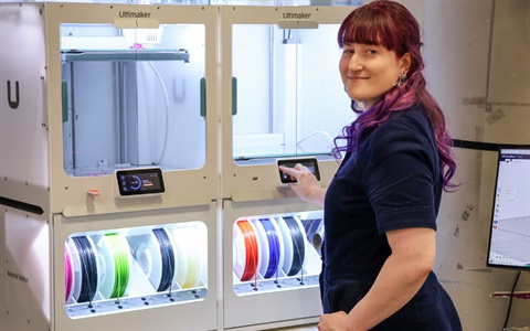 A female uses a 3-D printer at the Fab Lab. 