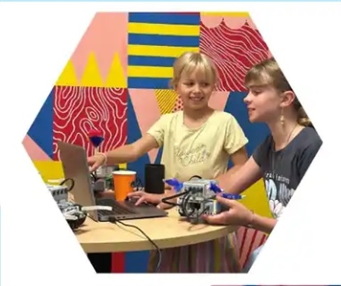 Two girls coding on a laptop with robot