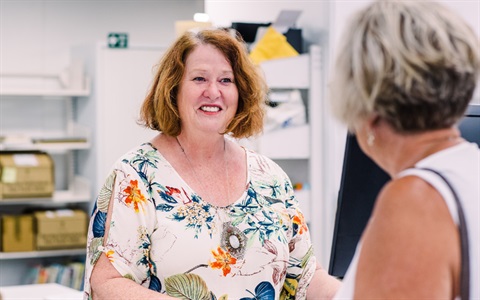 A female library staff member serves a borrower.